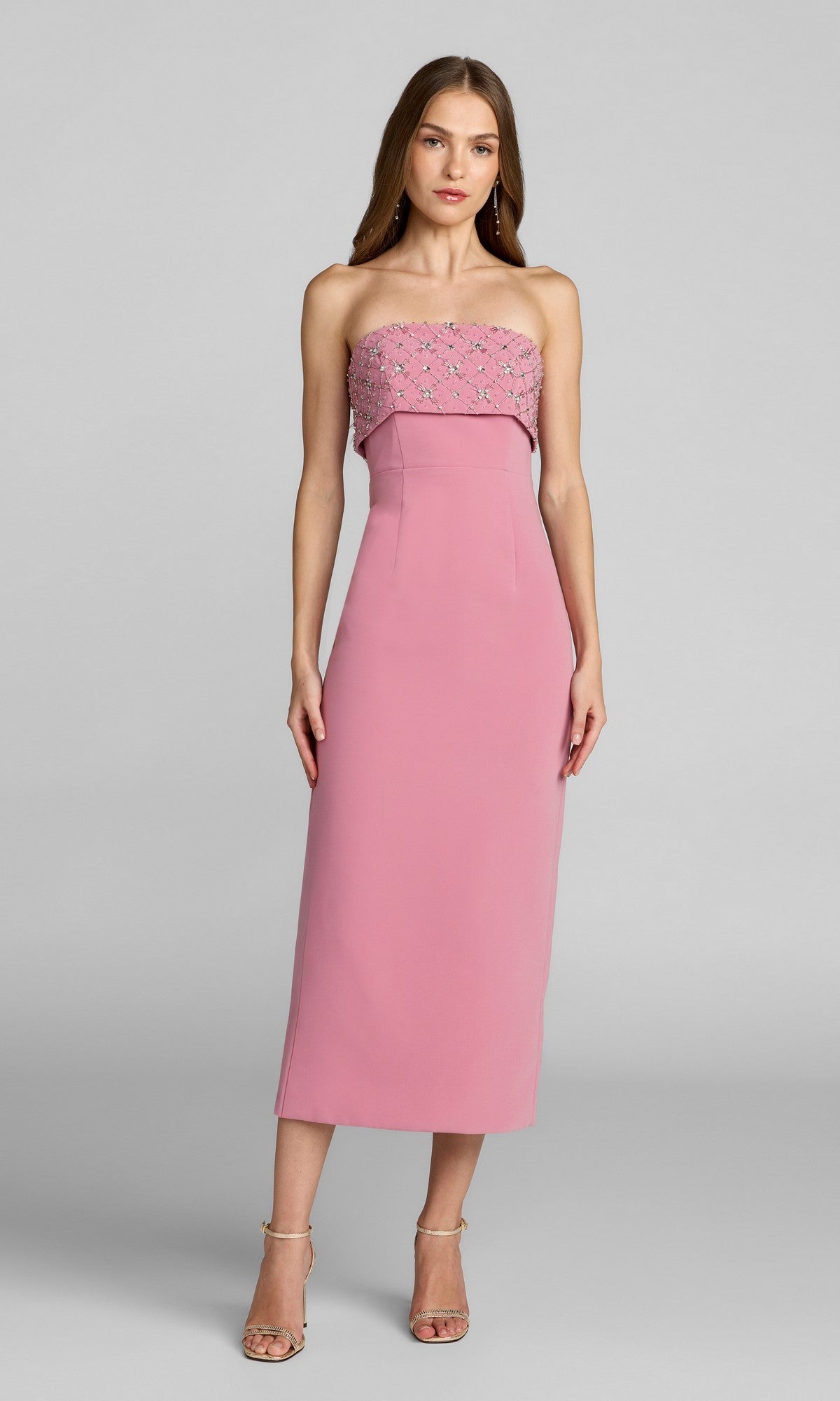 A woman wearing the Mac Duggal 11883 orchid midi wedding guest dress, strapless with floral and rhinestone details on the bodice, paired with strappy heels, stands against a plain gray background.